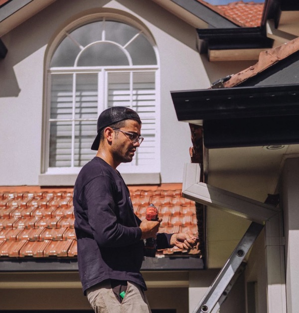 Team member working on roof drainage beside a downpipe