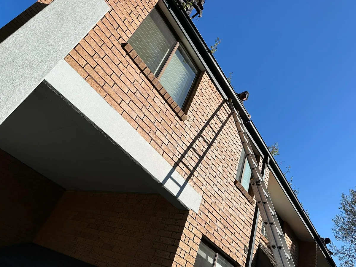 Close view of gutter installation work on a two-storey brick home