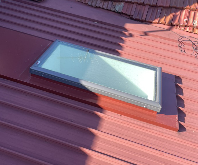 Skylight and surrounding flashing on a red metal roof in Sydney